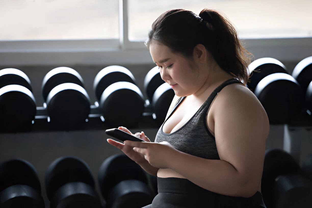 Wanita Asia Menggunakan Smartphone di Gym